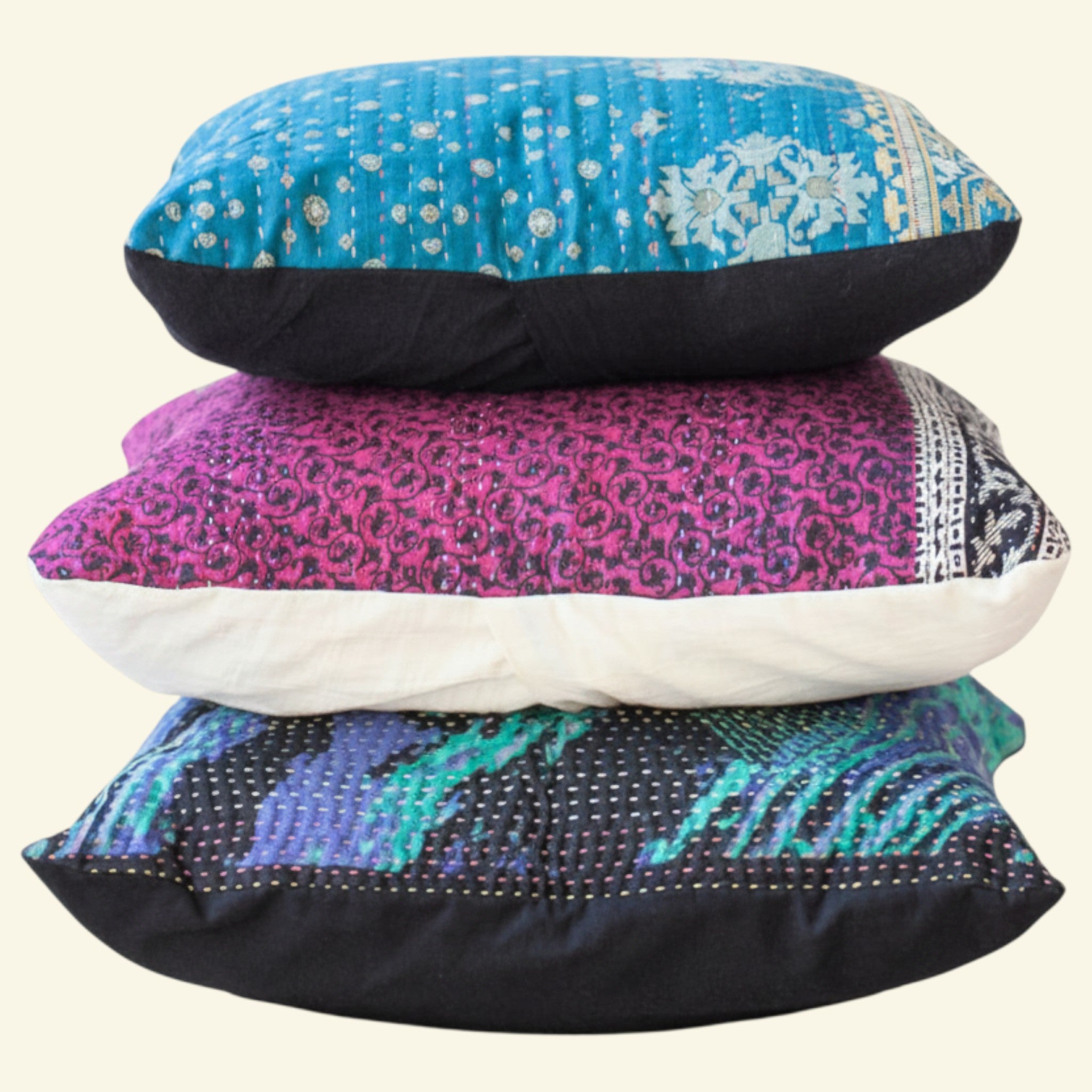 Stack of three decorative pillows with colorful patterns on a beige background