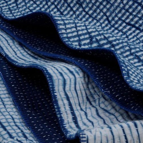 Blue and white patterned fabric stacked on a light gray background