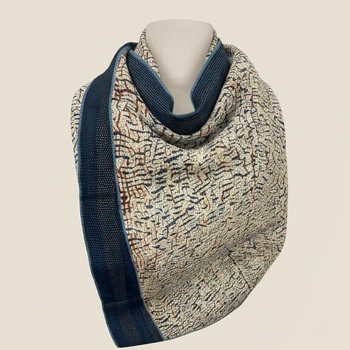 Four knitted scarves displayed on mannequins in a 2x2 grid, each with a different pattern and color combination including navy, beige, green, and blue.