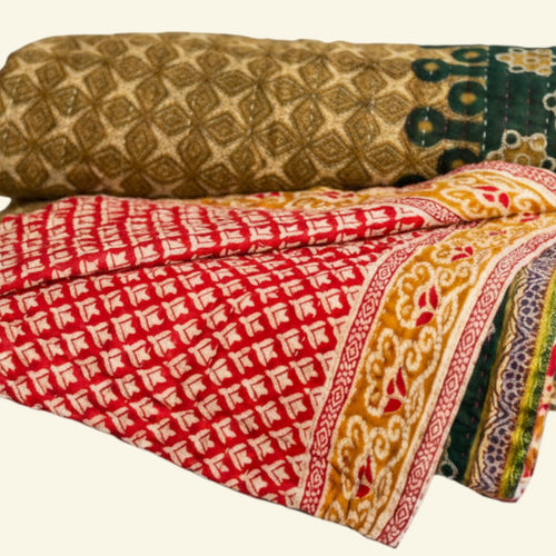Three folded patterned blankets on a beige background