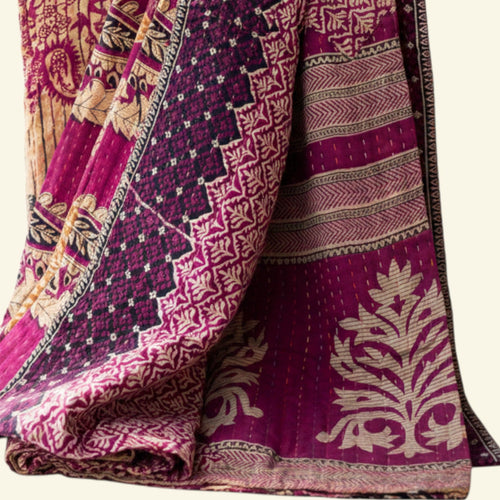 Folded fabric with intricate patterns in pink, purple, and beige on a white background