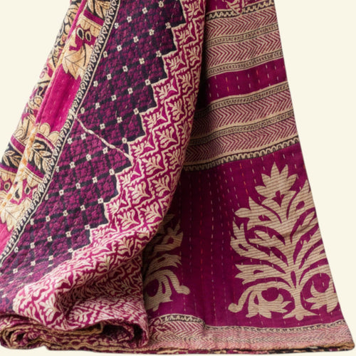 Folded purple and pink patterned fabric on a beige background