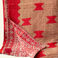Folded fabric with red and beige pattern on a light beige background