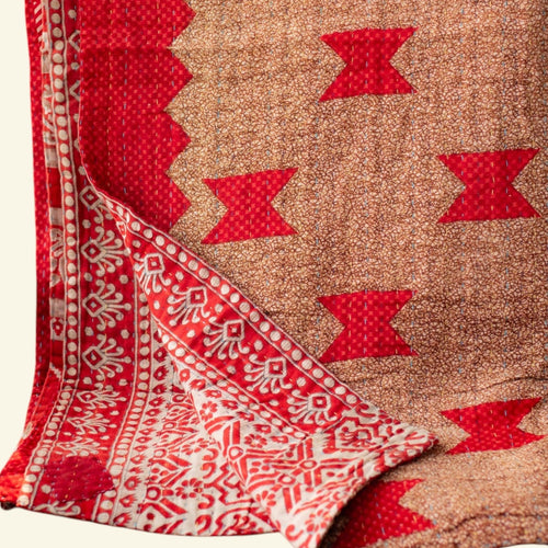 Folded fabric with red and beige pattern on a light beige background