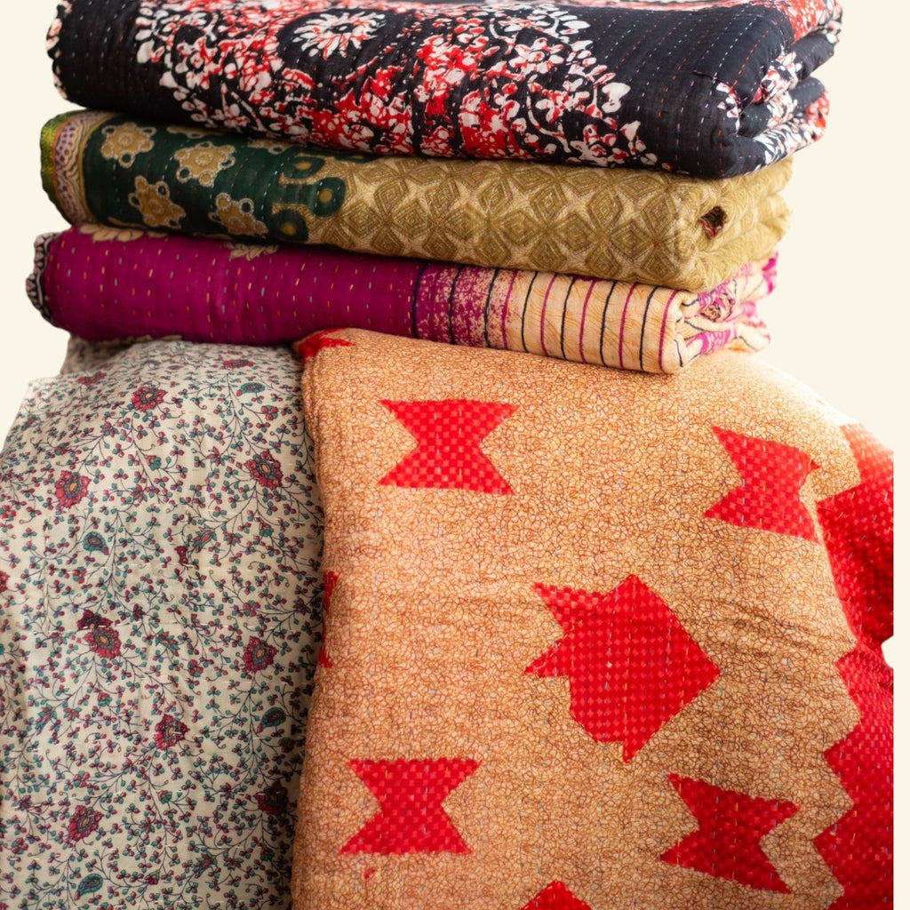 Stack of patterned quilts on a white background