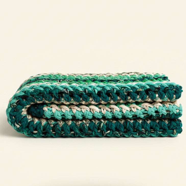 Colorful knitted blanket draped over a wooden stool on a beige background