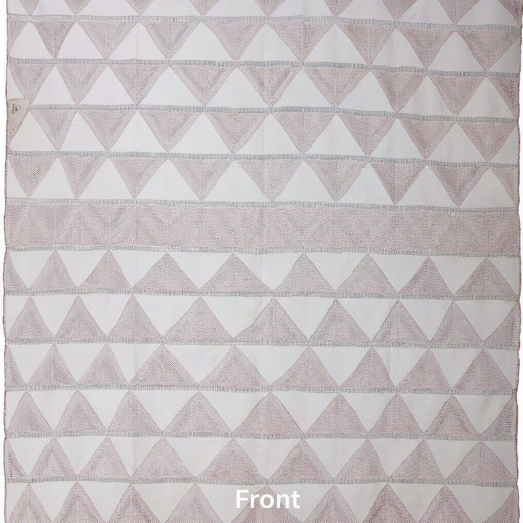 Geometric triangle patterned blanket with soft pink and white colors on a plain background