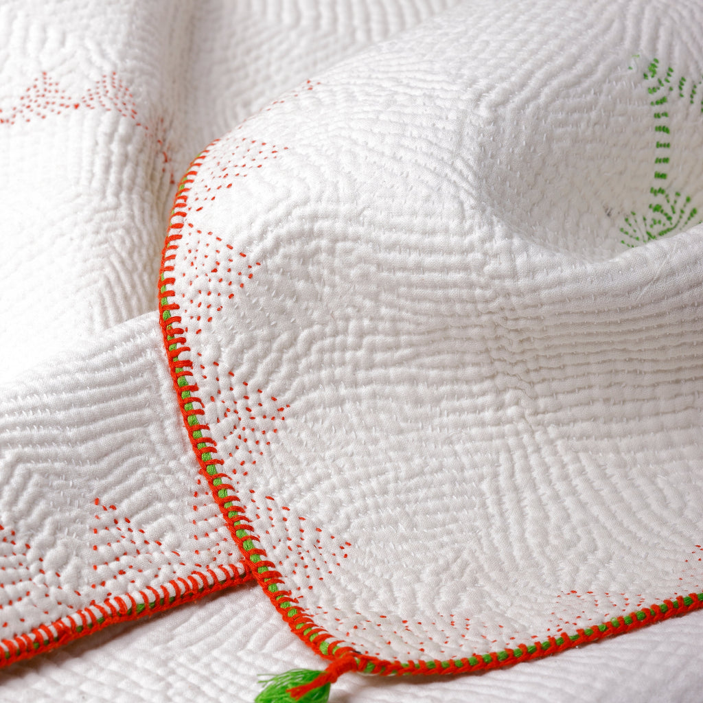 Close-up of a textured white fabric with orange trim and green accents on a white background