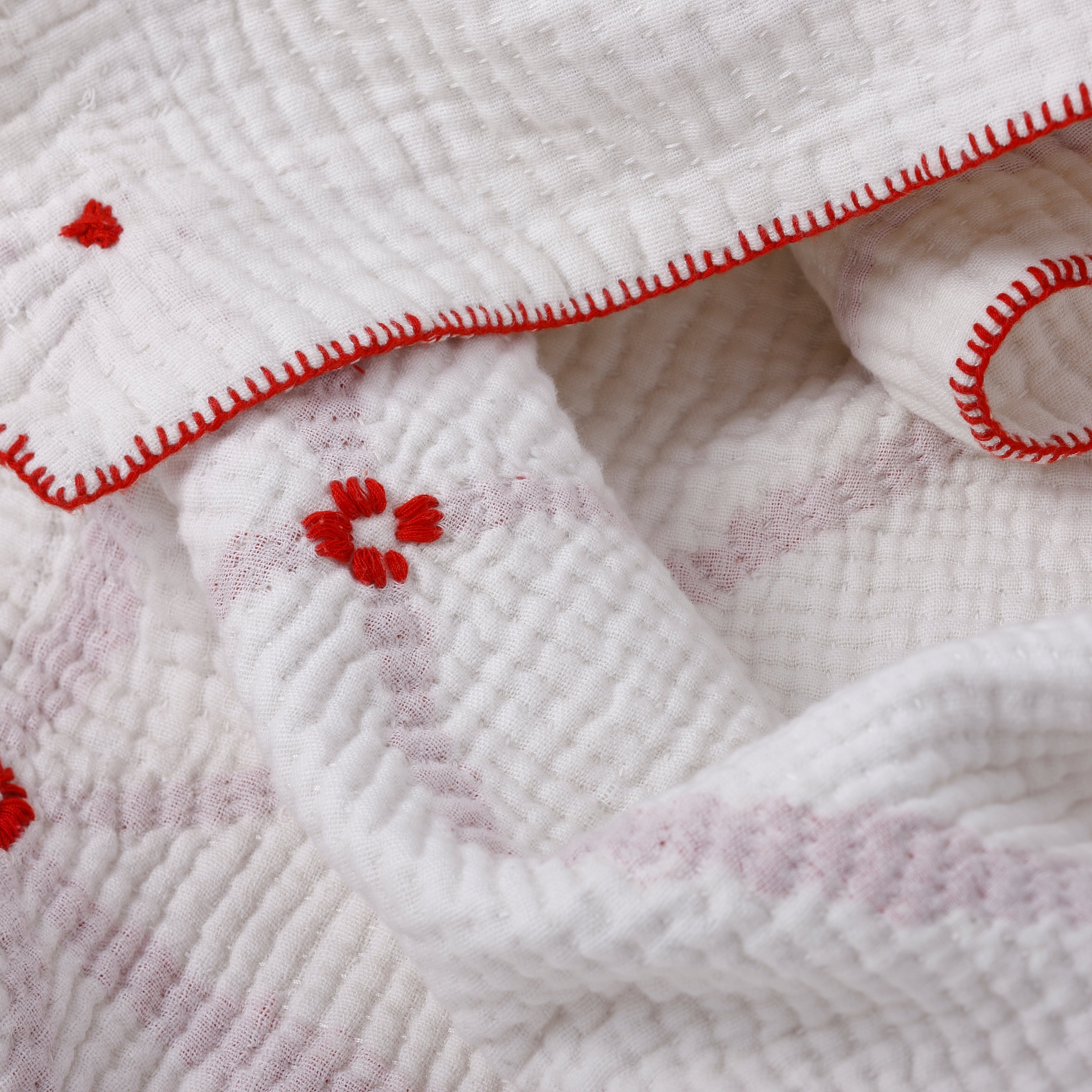 Close-up of a white textured fabric with red floral embroidery