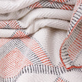 Close-up of a textured blanket with red and black patterns on a white background