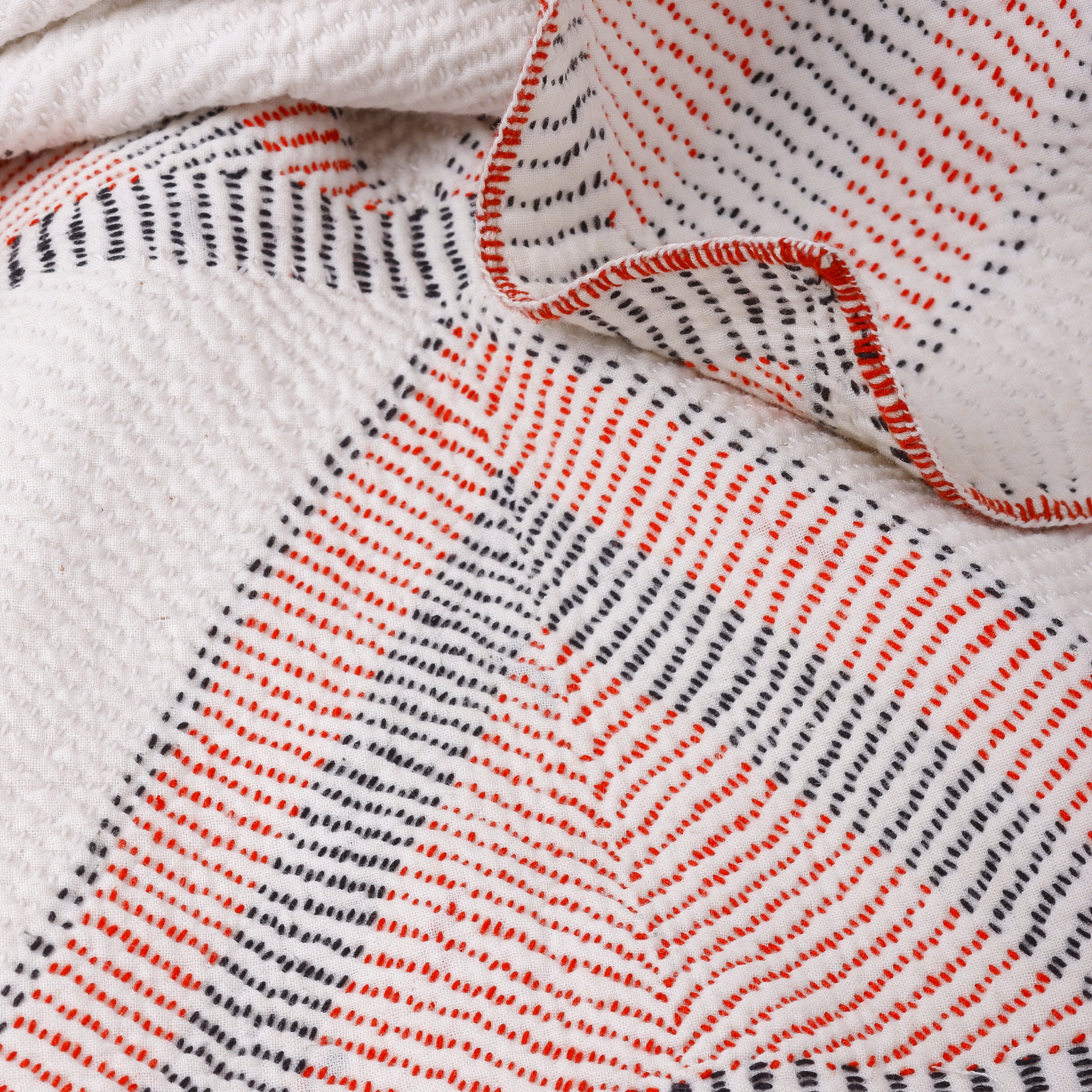 Close-up of a textured fabric with red and black patterns on a white background