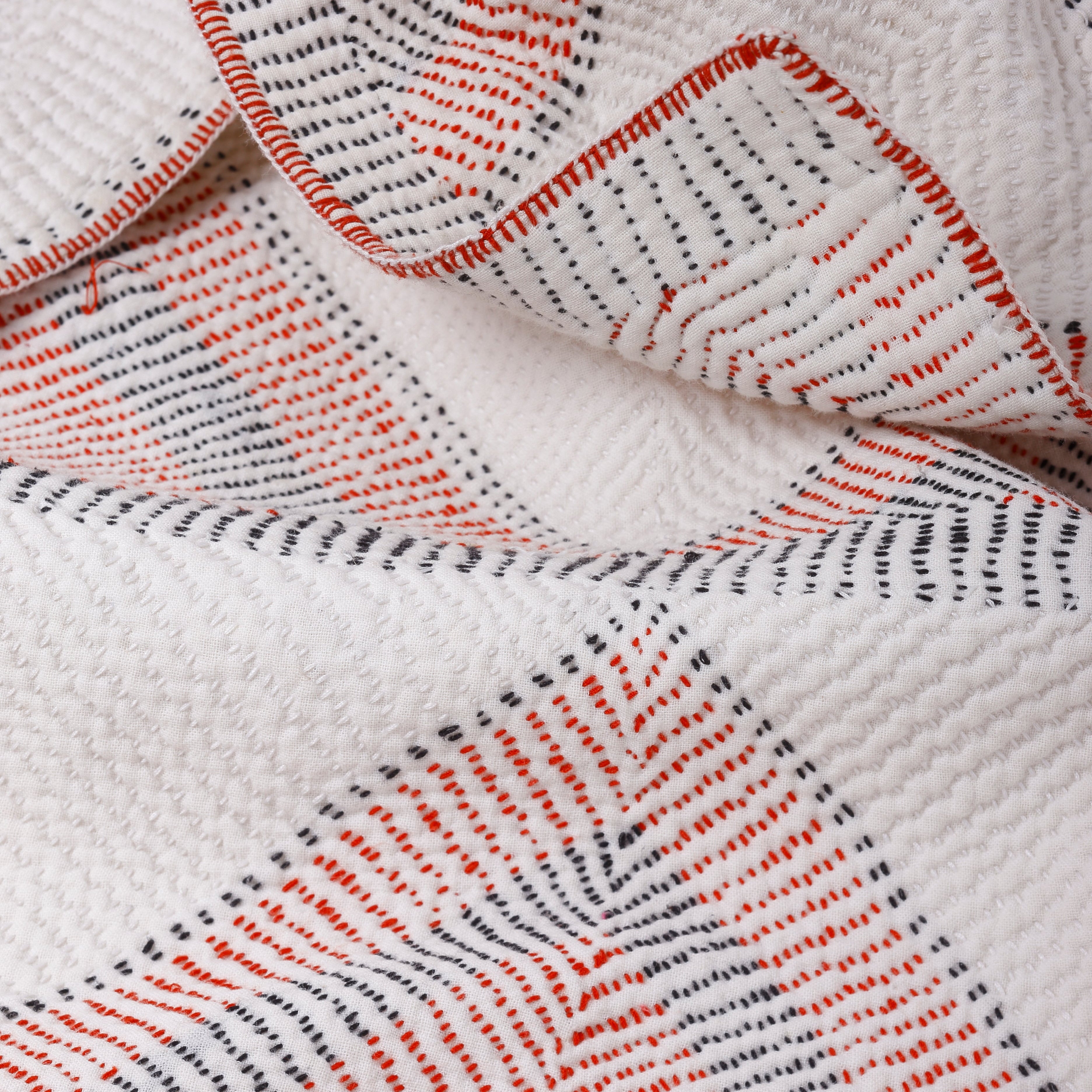 Close-up of a textured fabric with red and black patterns on a white background