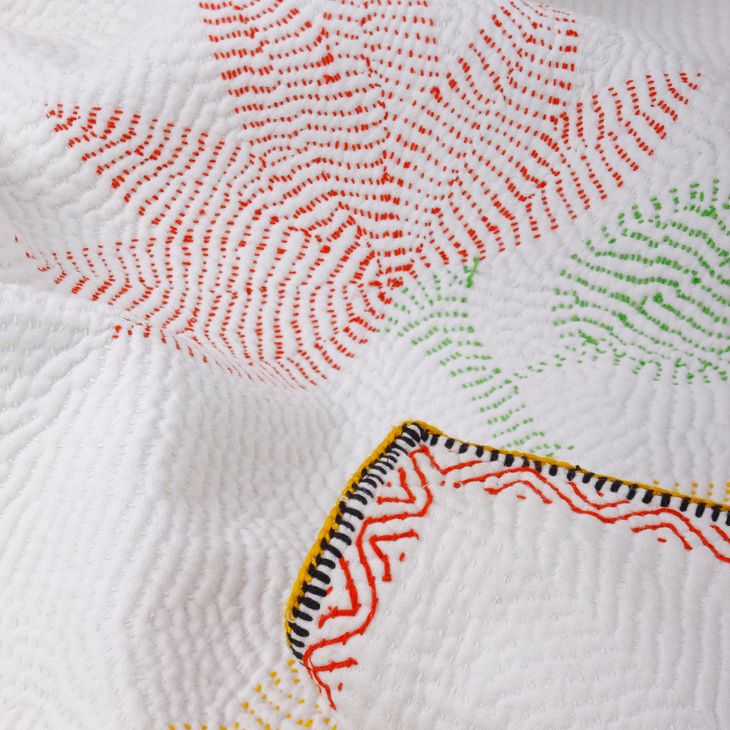 Close-up of a quilt with colorful geometric patterns on a white background