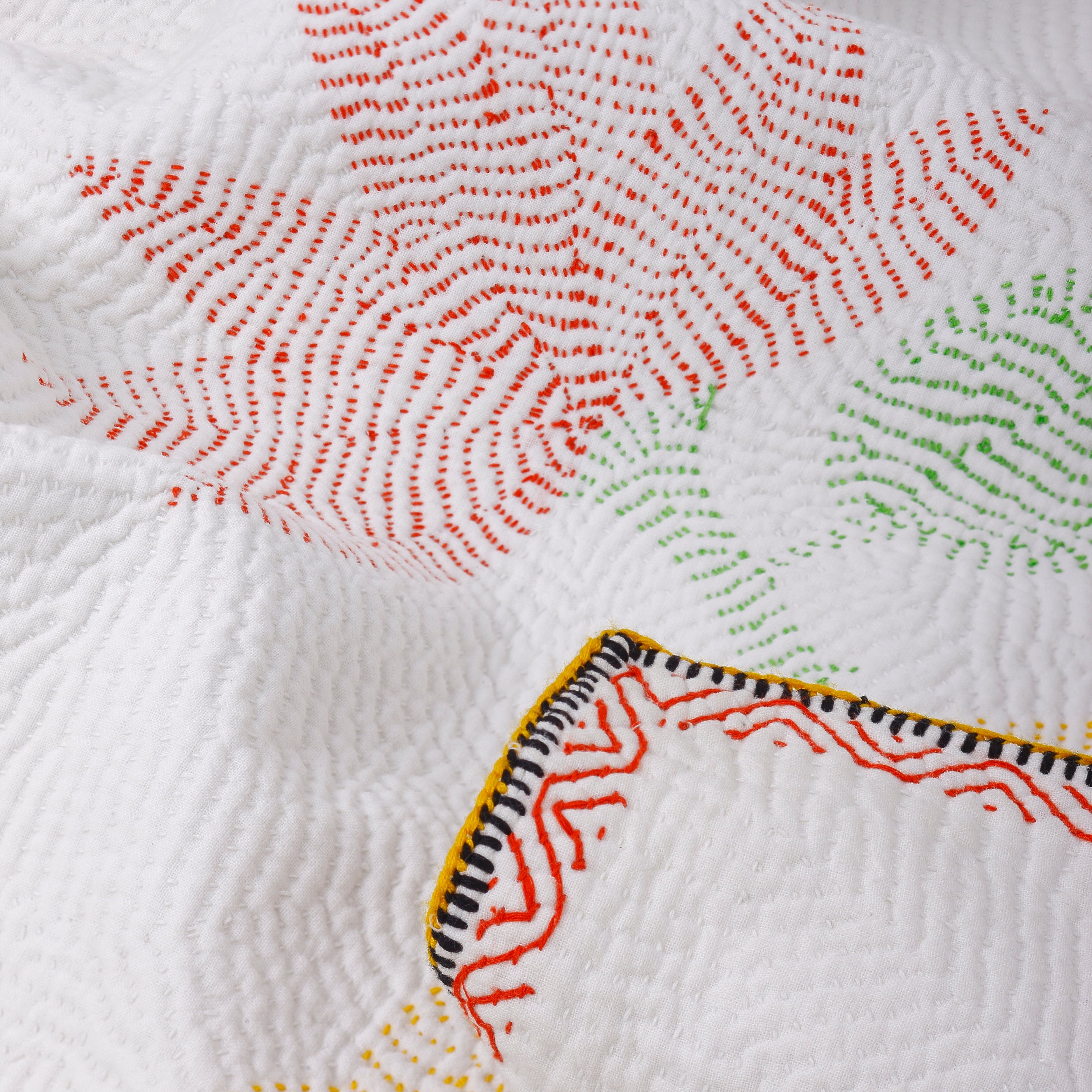 Close-up of a quilt with colorful geometric patterns on a white background