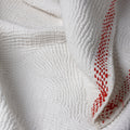 Close-up of textured white fabric with red stitching detail