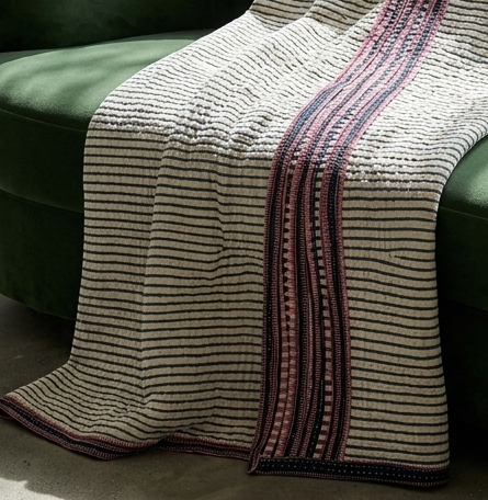 Textured blanket with striped pattern draped over a green couch